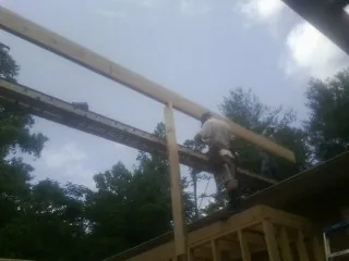 Carpenter setting a ridge beam over a new addition frame — Ice Dam Removal by Roofing Brothers in Garden City